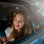 タクシーで携帯を見る女性