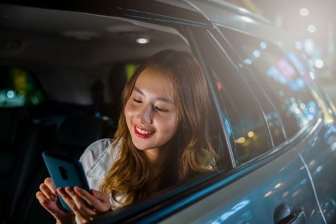 タクシーで携帯を見る女性